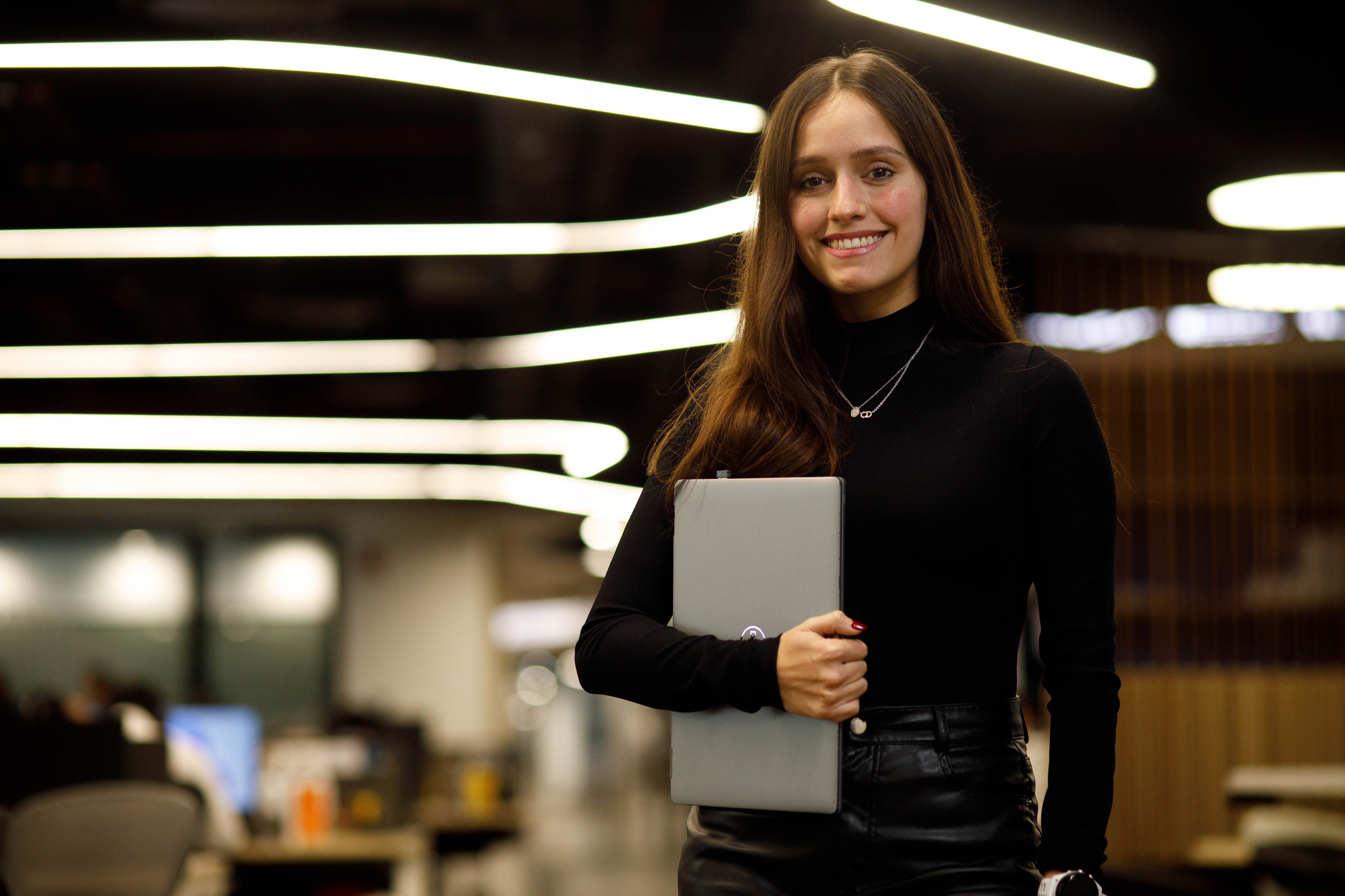 Employee standing in the office holding their laptop