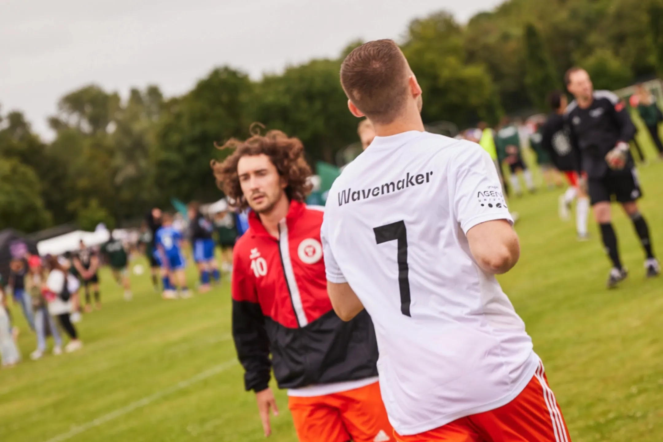 Group of people playing football on a grass pitch