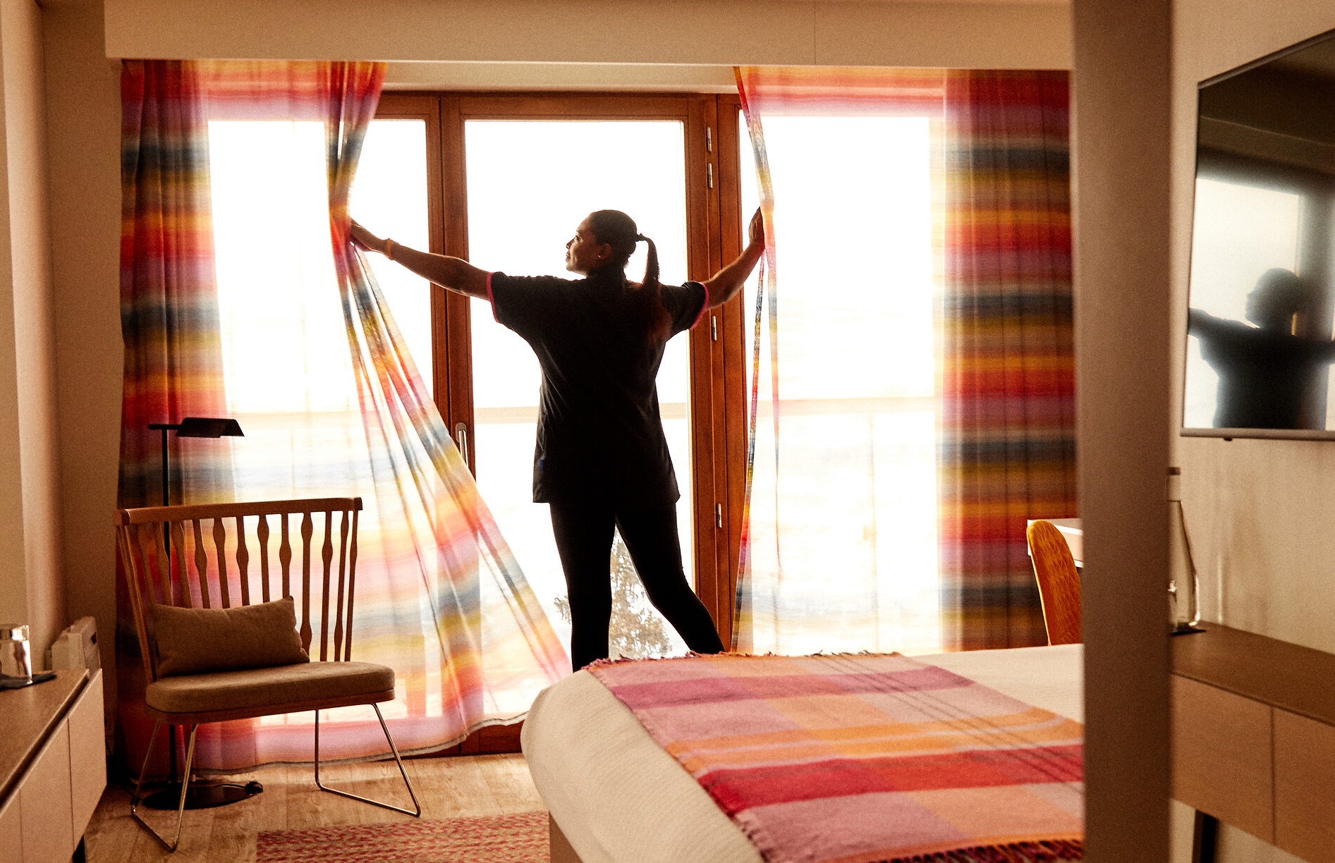 A G.E Housekeeper opening the curtains in a room of one of our Club Med Resort