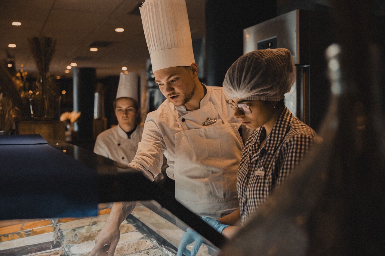 A cook giving a lesson in the kitchen to employees.