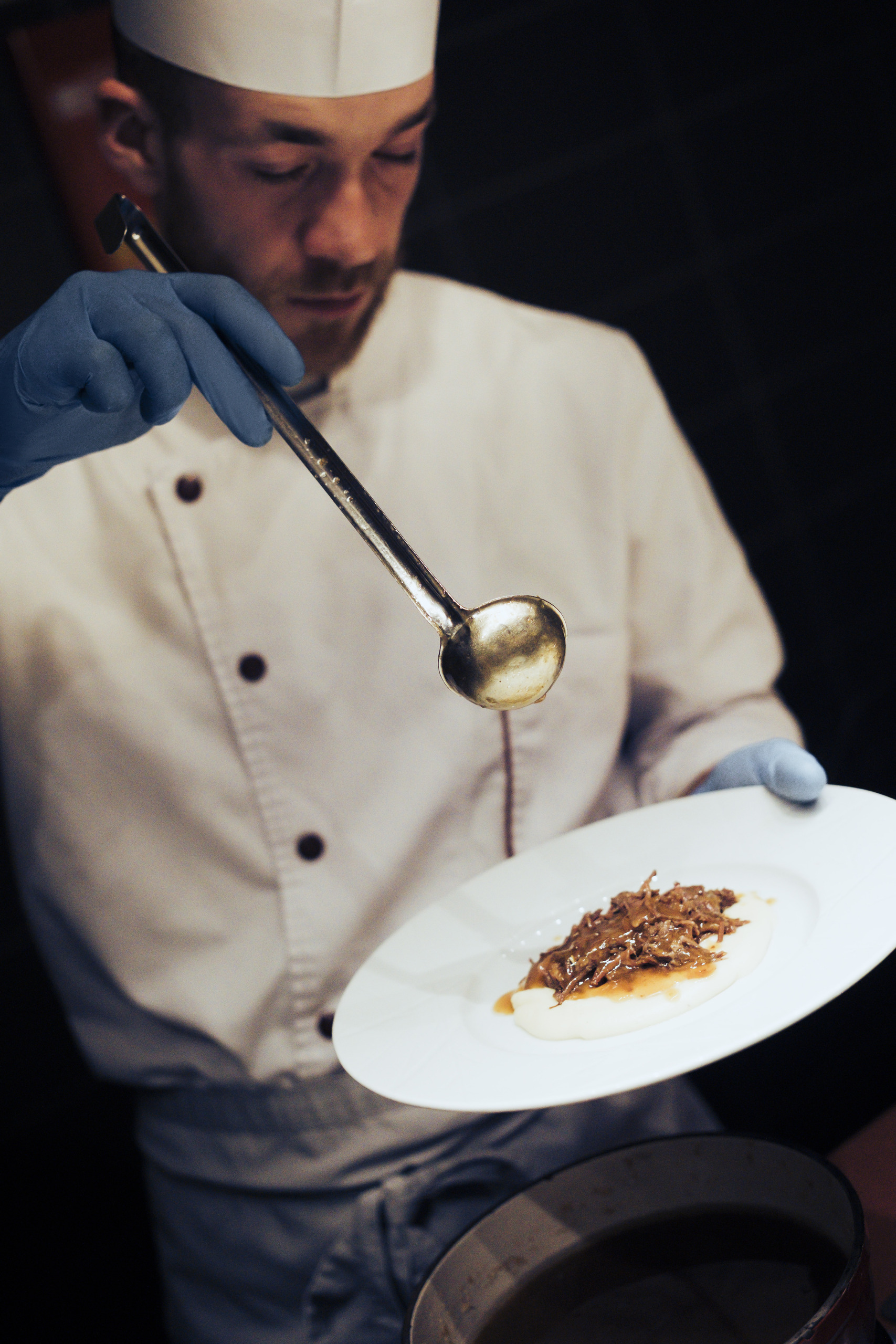 A Chef de Partie putting sauce in a dish