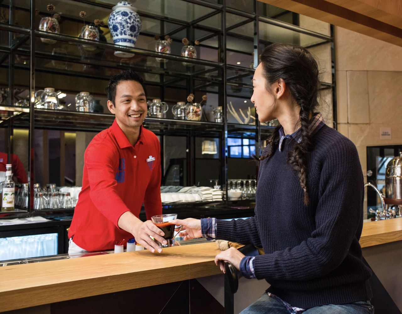 A G.O bartender serving a drink to a client.