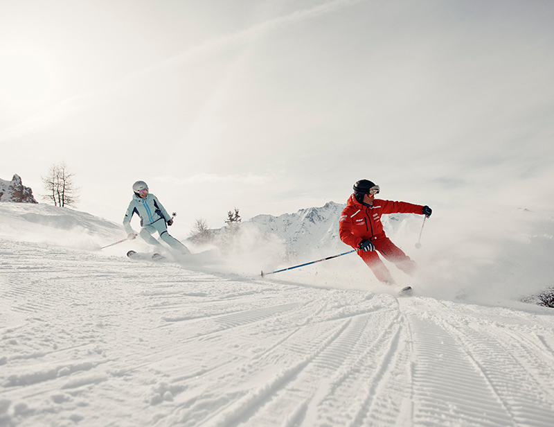A ski instructor skiing on the slopes with a client