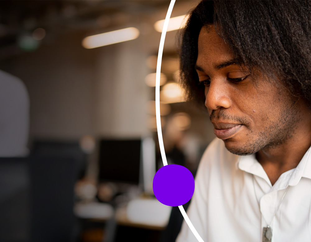 A man in a white shirt focusing in a busy office.