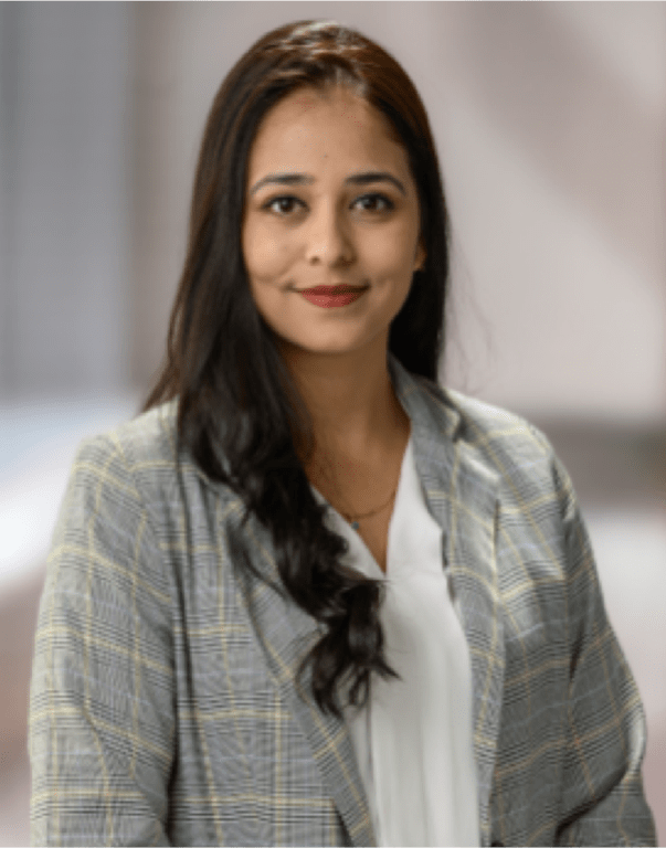 Professional woman in a grey plaid blazer and white blouse standing in a modern office setting