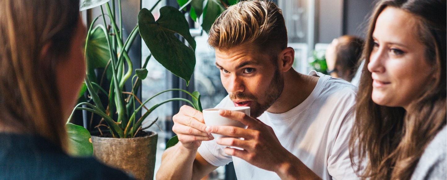 A man drinking tea next to two other friends