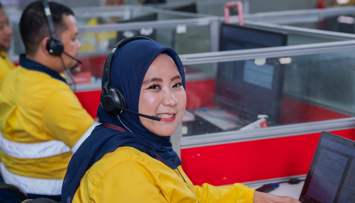 Smiling woman with headset working at computer in office