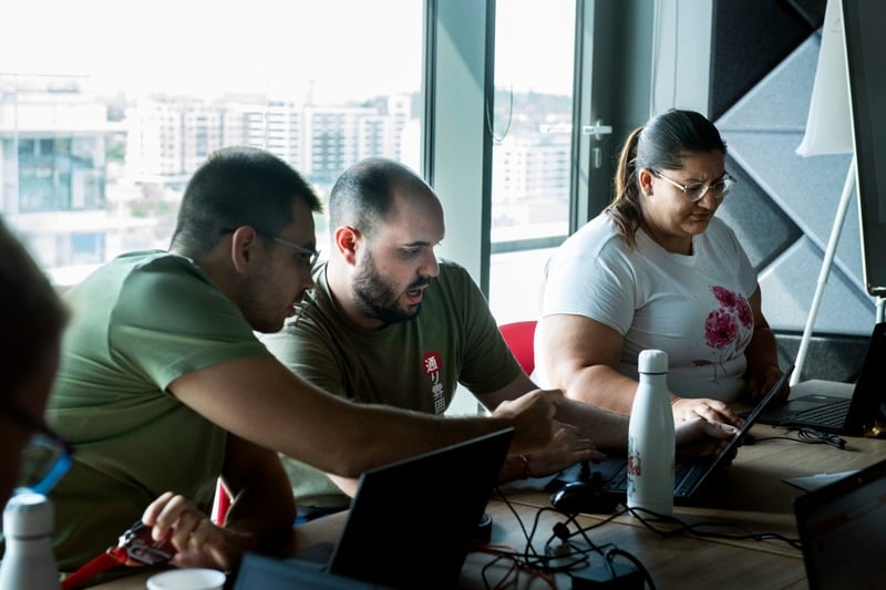 Team members collaborating on laptops in a modern office