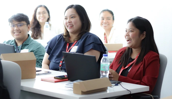 Group of colleagues smiling during meeting with laptops and notebooks