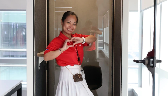 Smiling woman making heart gesture in office booth
