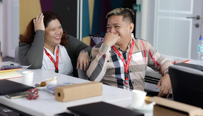 Two coworkers laughing together at a meeting