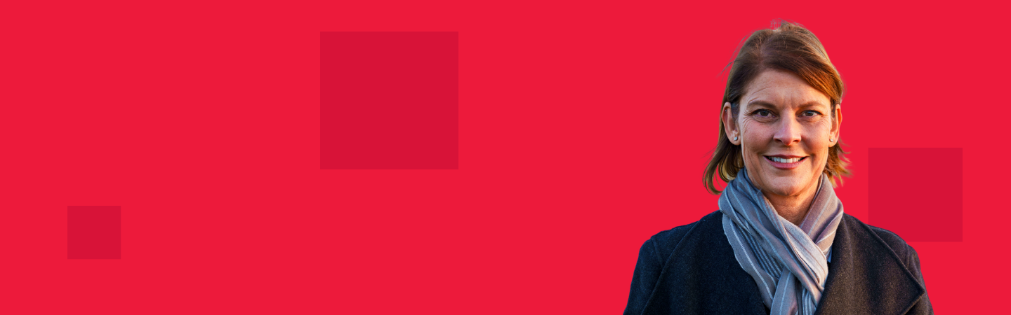 Red background with dark red square pixels on top, with a woman in a jacket and scarf looking at the camera and smiling