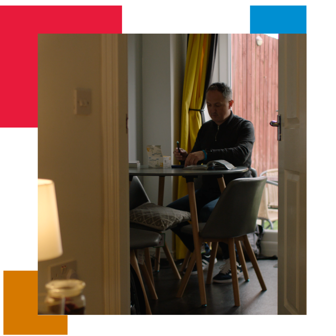 Man working at a table in his house, looking out through a door