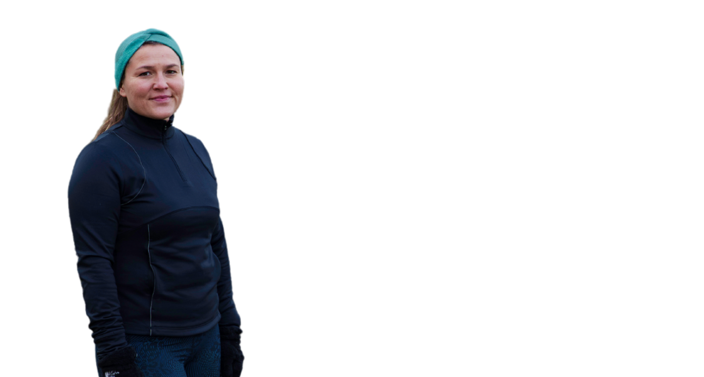 Woman in running gear standing up and looking at camera, wearing dark clothing