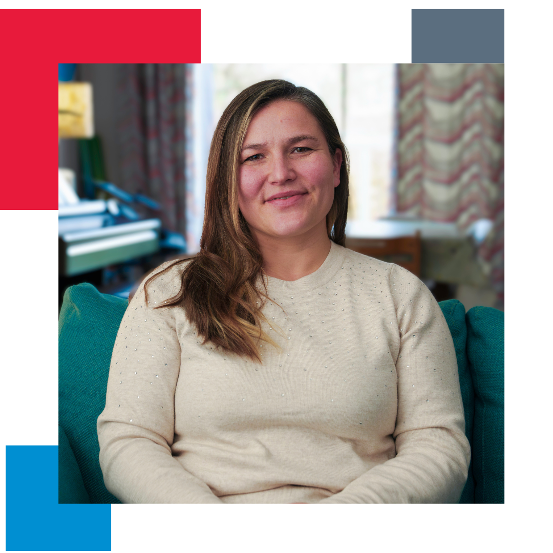 Woman sitting in her living room looking straight at the camera with a border of coloured pixels in the background