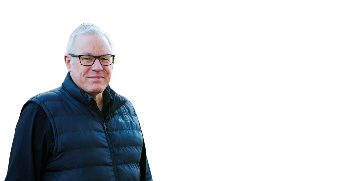 Man in dark gilet with glasses and white hair, looking at the camera