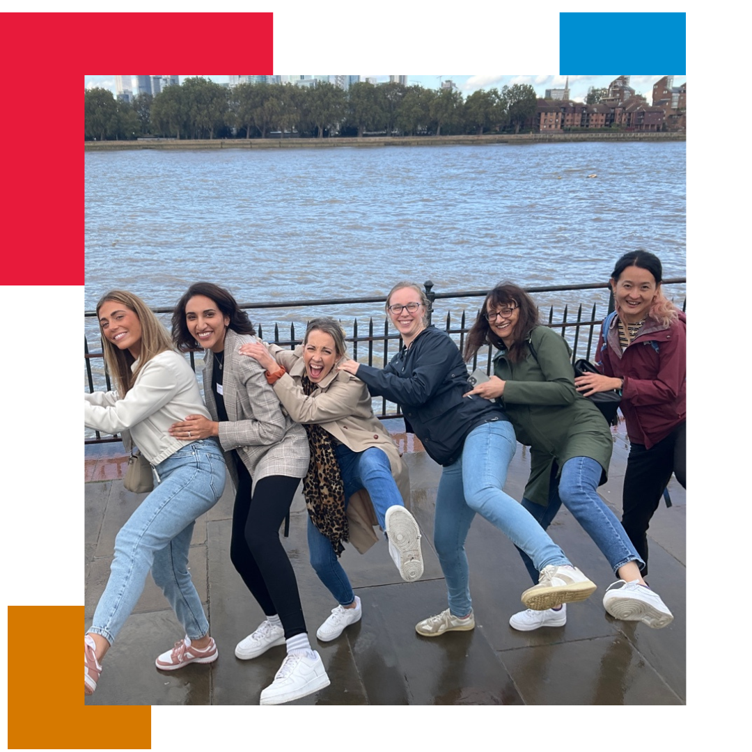 Group of people in a line, doing a conga by the side of a river