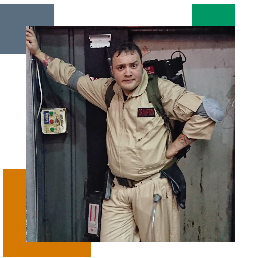 man dressed in ghostbusters outfit, looking at the camera, leaning against a wall