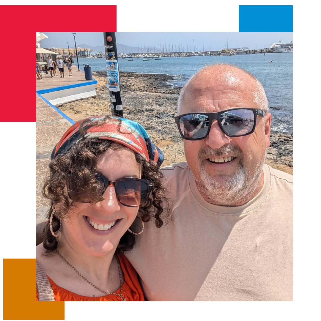 Woman and man on a beach wearing sunglasses taking a selfie, looking into the camera