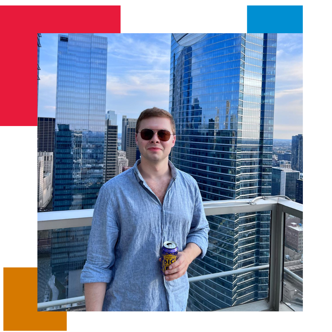 Man holding a beer with sunglasses on, standing in front of some skyscrapers