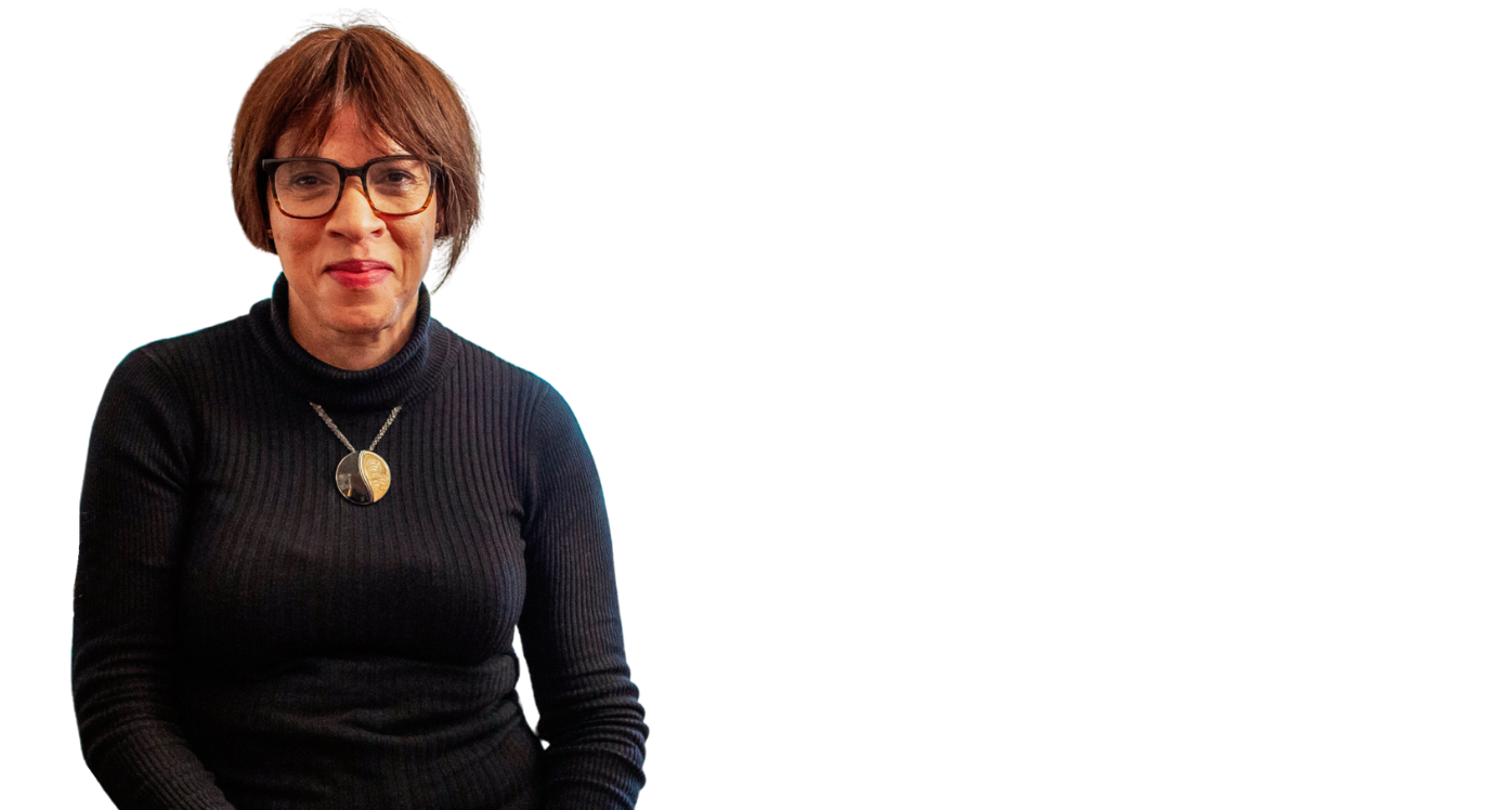Woman in dark top and glasses with gold necklace, smiling at the camera