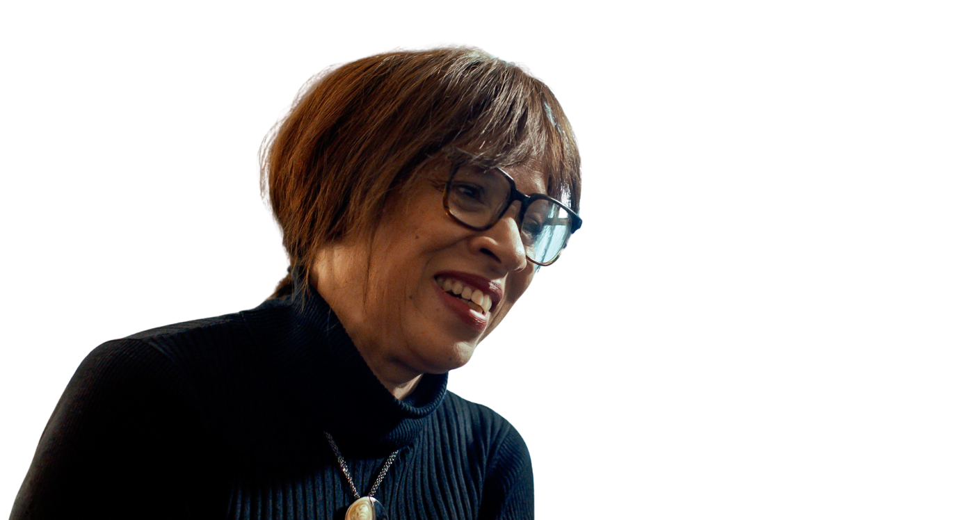 Woman in dark top and glasses with gold necklace, smiling