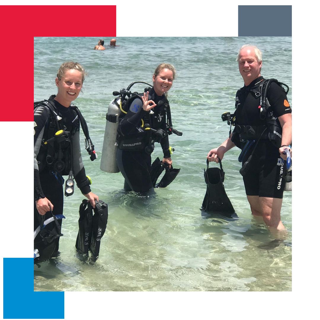 3 people in scuba diving gear in the sea posing for a photograph