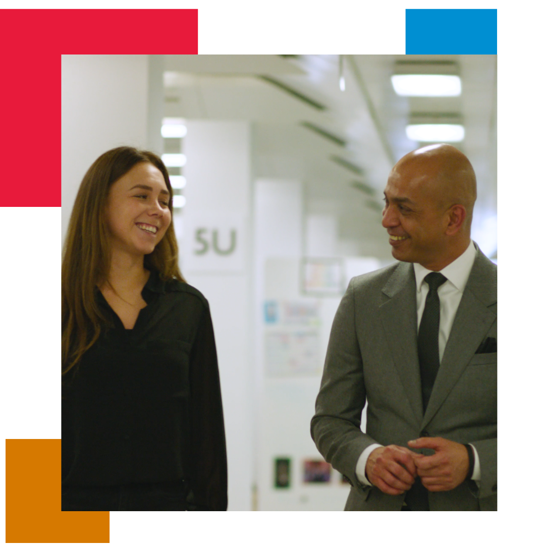 Man walking in office corridor with woman, laughing together