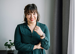 Claire draag een groene bloese en glimlacht