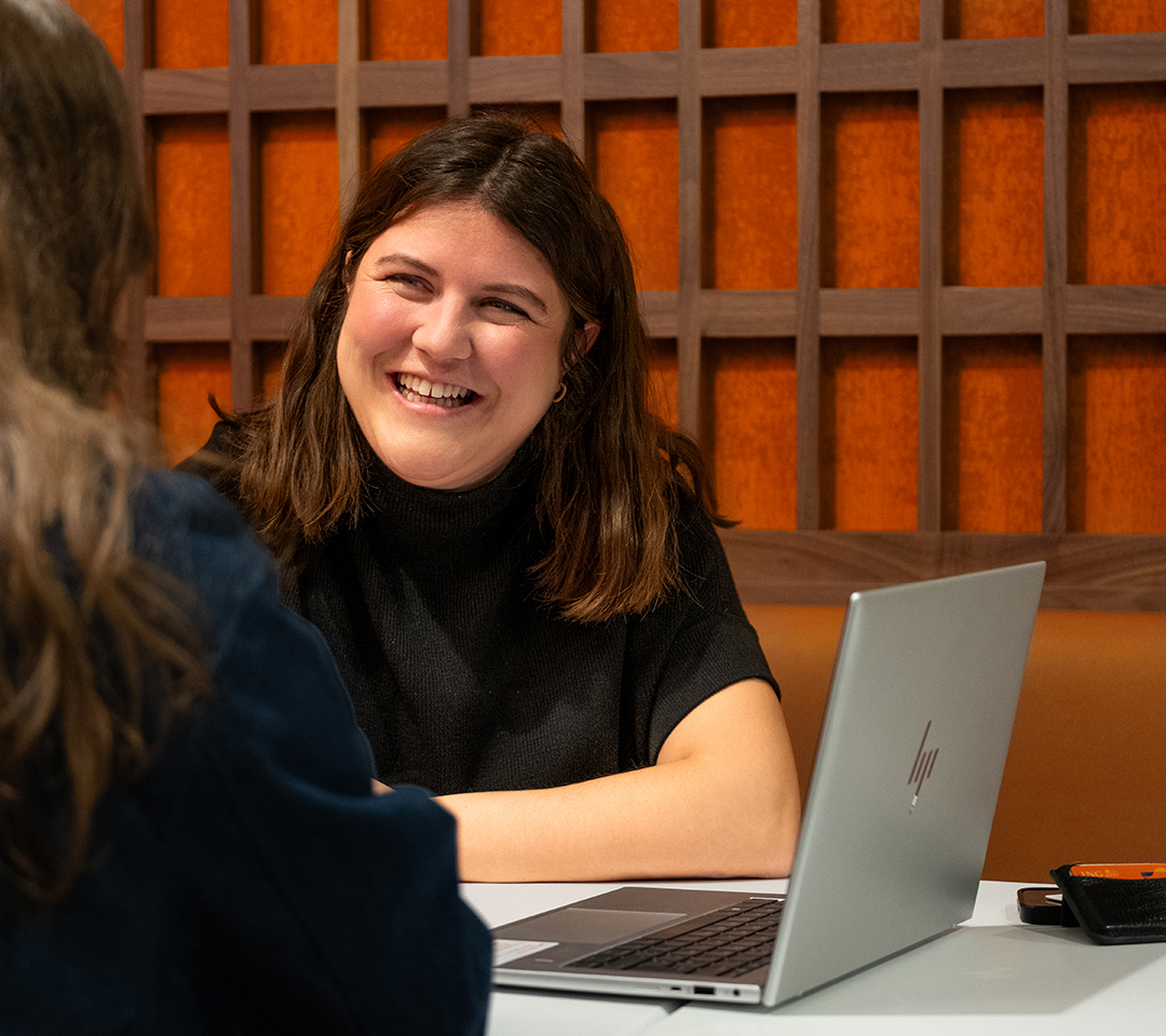 Alix is smiling, next to her laptop