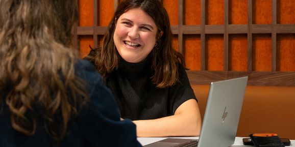 Alix, a young woman with long brown hair, in front of her laptop.