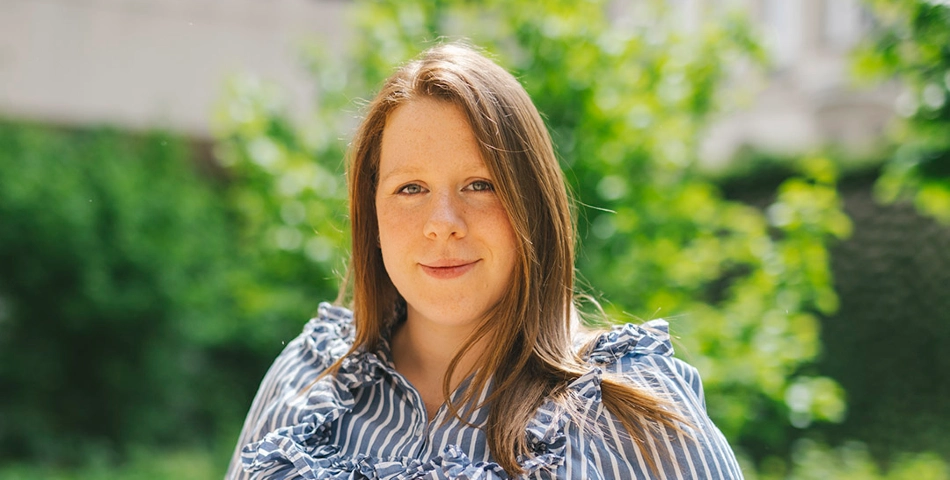 A woman with long brown hair in front of a green background