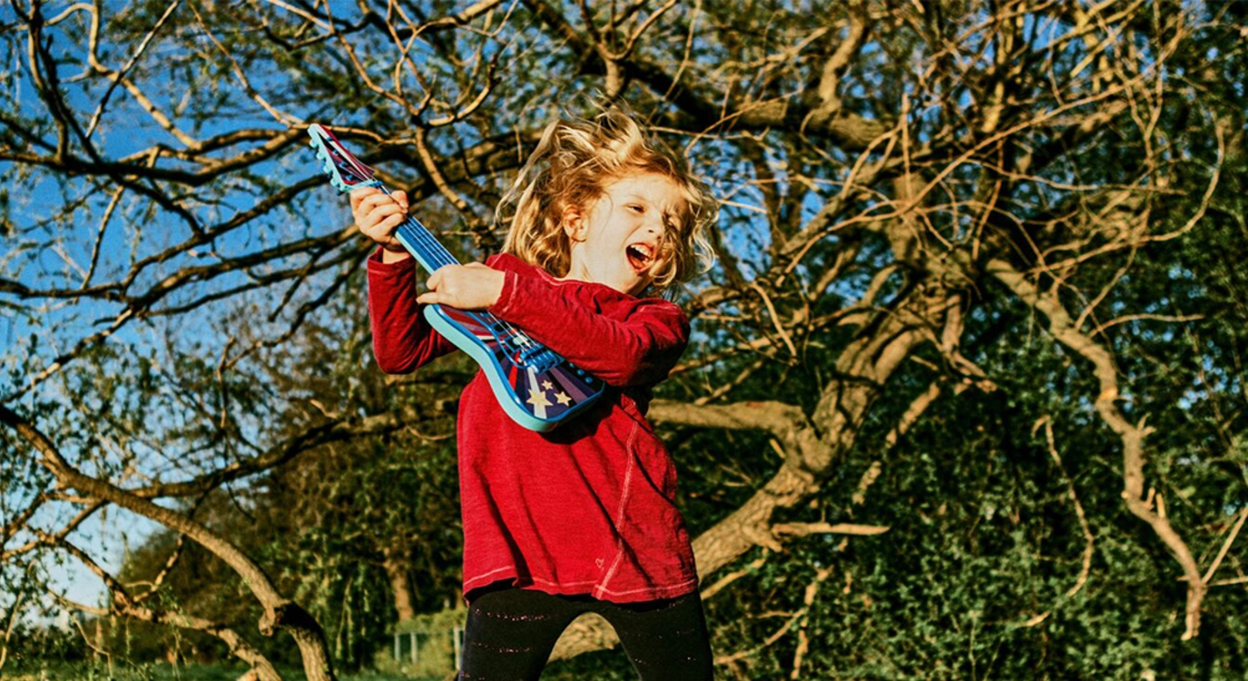 young girl jumping and playing the guitar