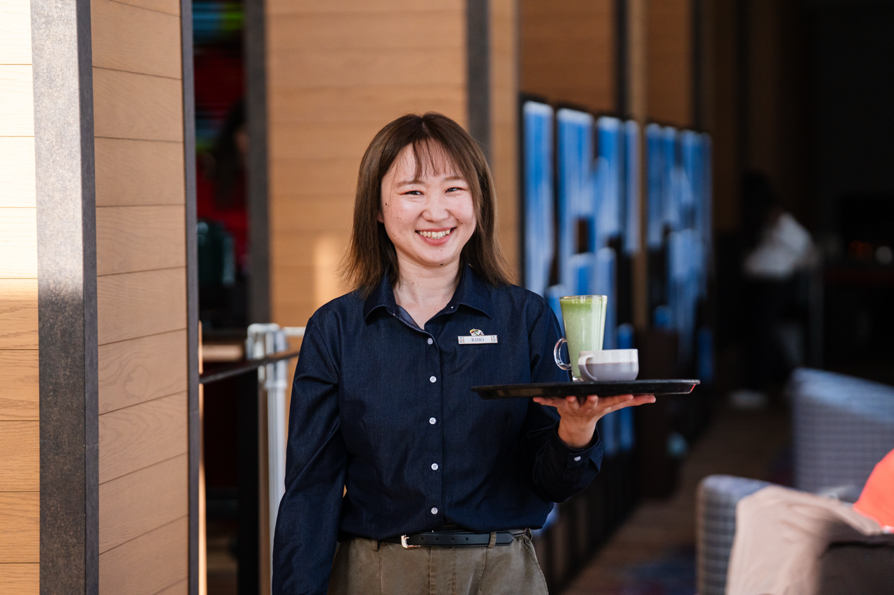 A barmaid holding two drinks on a tray