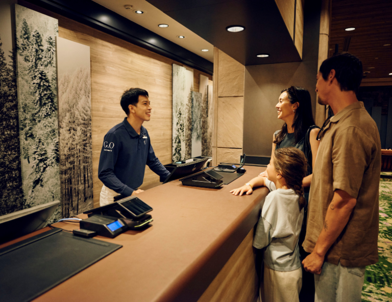 Club Med receptionist welcoming guests at the resort front desk, providing personalized customer service and ensuring a smooth check-in experience.