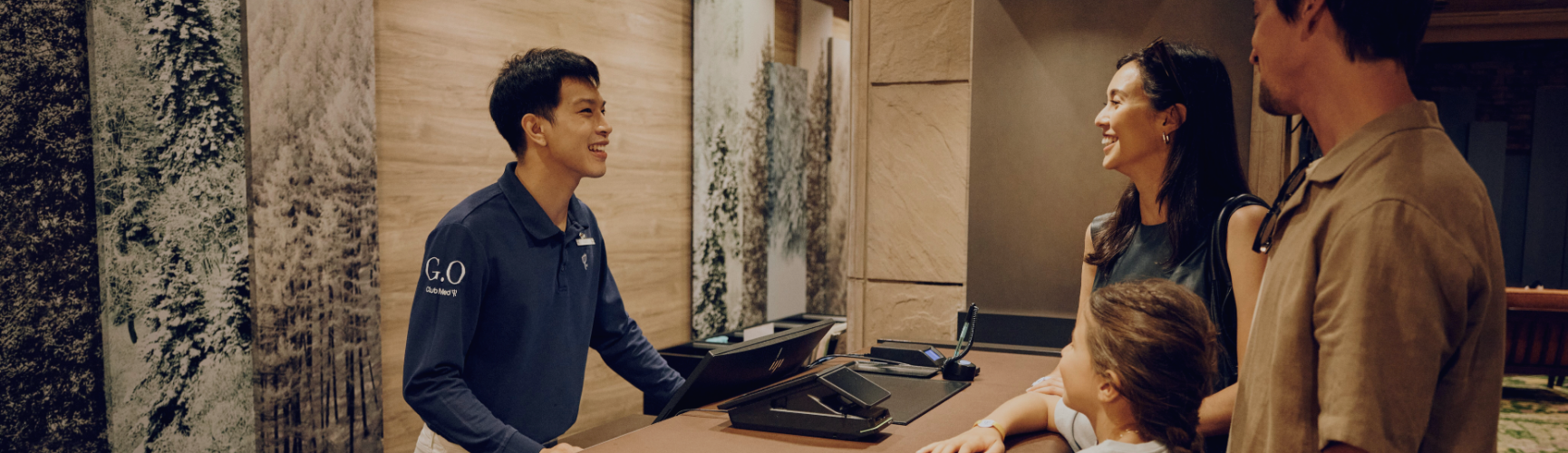 Club Med receptionist welcoming guests at the resort front desk, providing personalized customer service and ensuring a smooth check-in experience.
