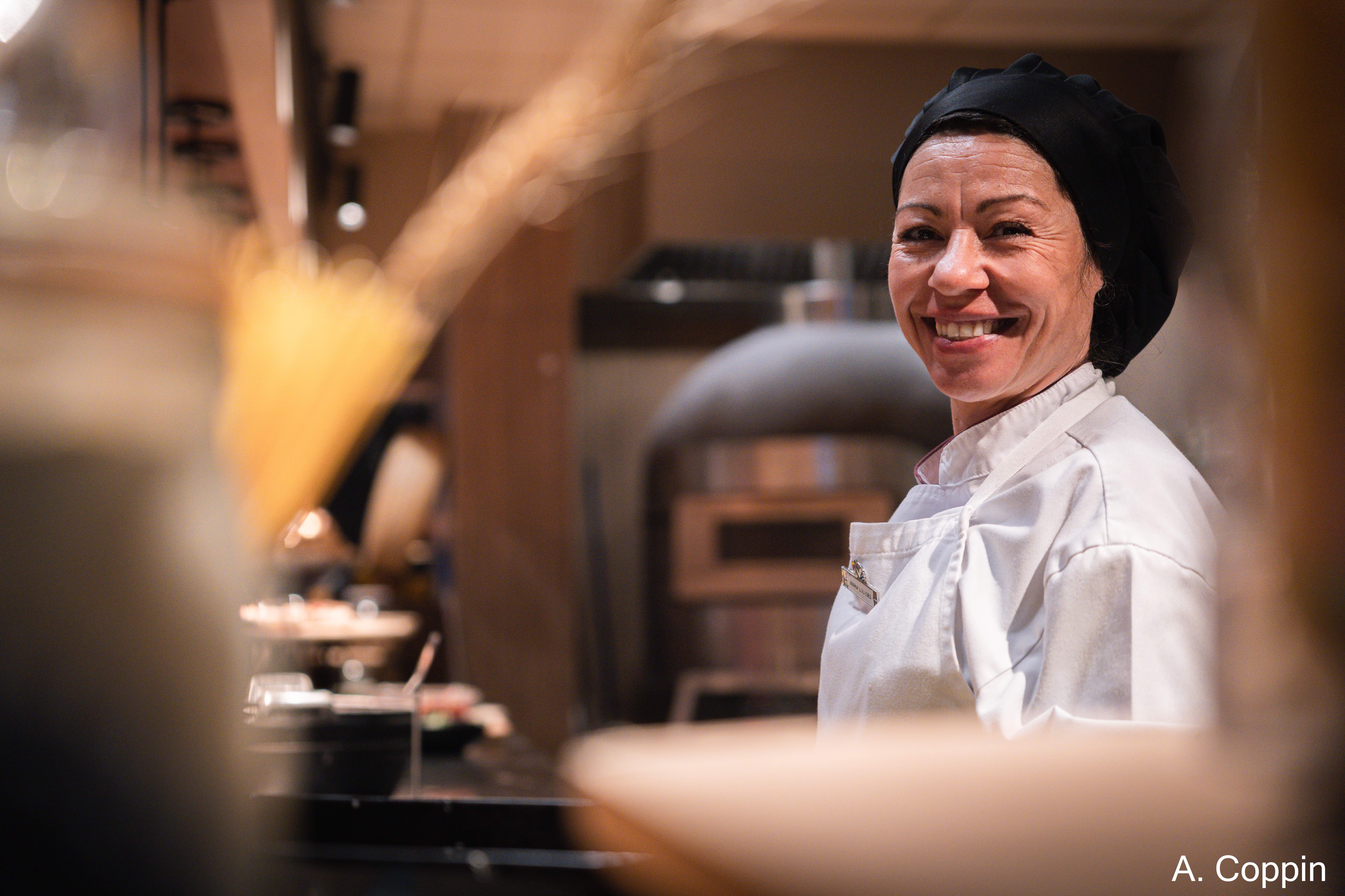Une Cuisinière qui sourit face à la caméra dans un restaurant Club Med