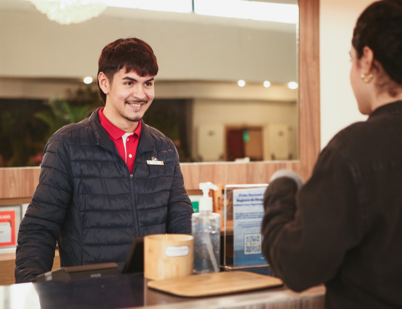 Club Med receptionist welcoming guests at the resort front desk, providing personalized customer service and ensuring a smooth check-in experience.