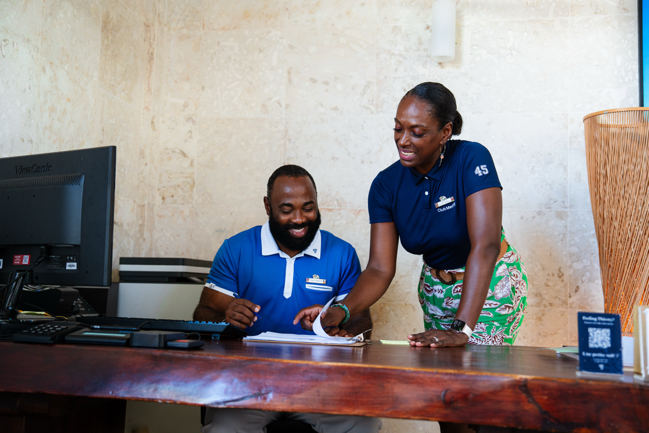 A Receptionist and his Manager are talking behind a reception desk