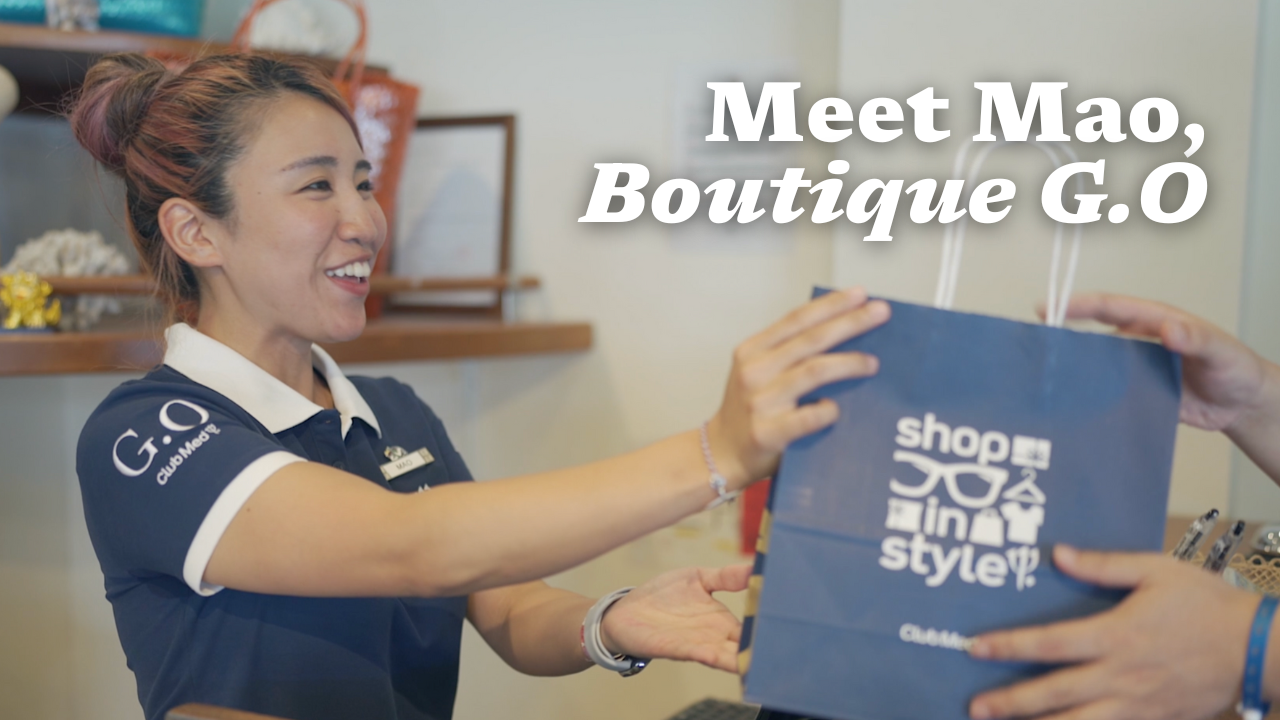 A boutique manager smiling and giving a shopping bag to a client