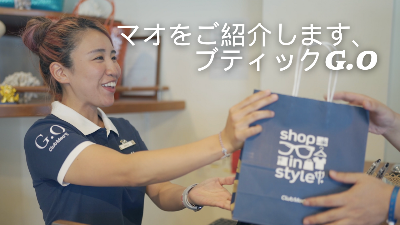 「ブティックマネージャーが笑顔でお客様にショッピングバッグを渡している様子」