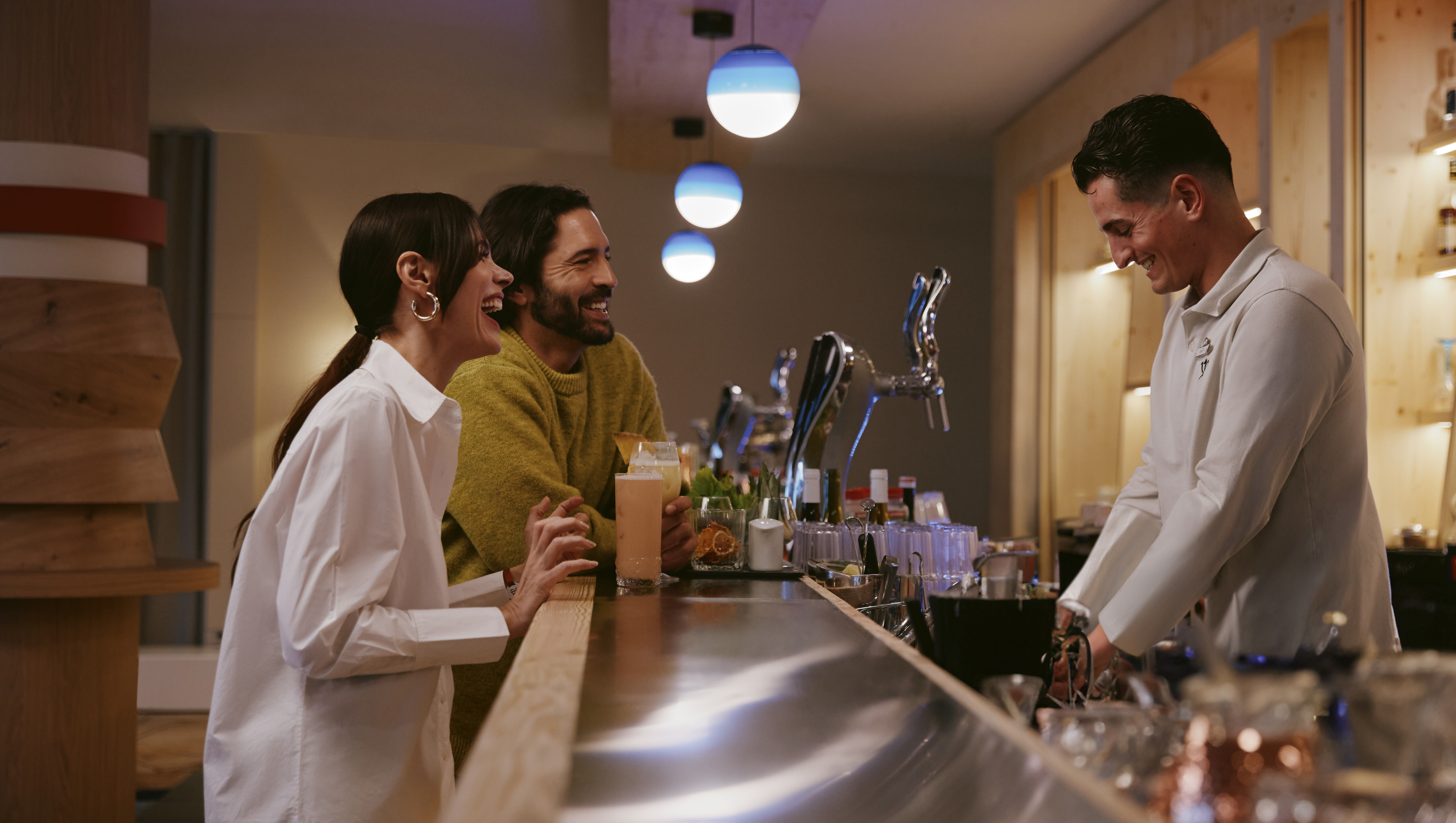 A bartender behind a bar, in front of two clients.