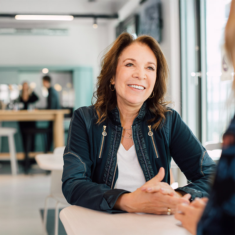 Sanofian sat at desk talking to colleagues in office