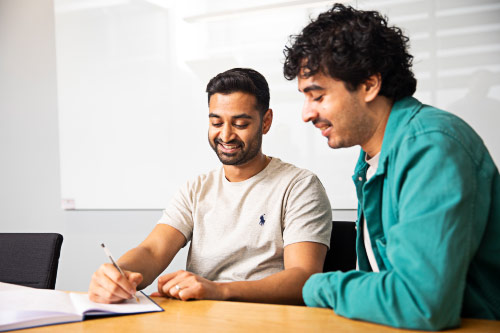 two people at a desk discussing work