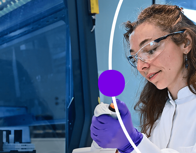 Woman in lab coat and glasses uses a pipette to distribute specimen