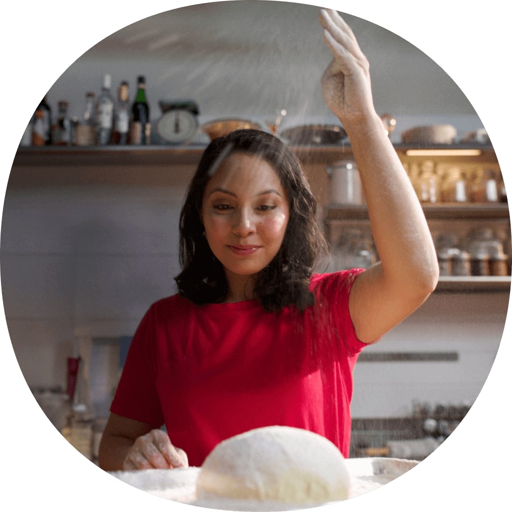 Femme en cuisine, saupoudrant de farine sur la pâte à pain