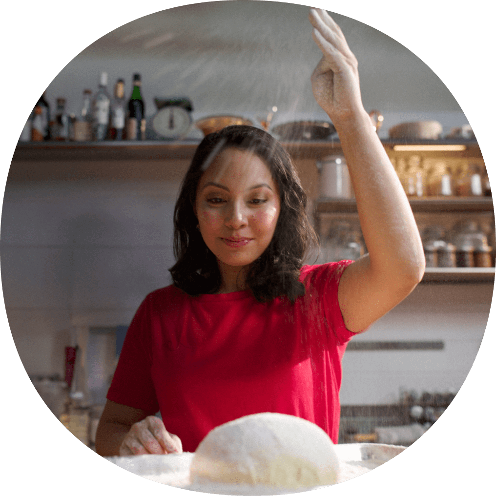 Woman in kitchen, sprinkling flour onto bread dough