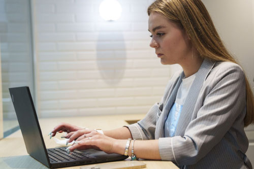 Femme travaillant sur un ordinateur portable, assise à un bureau