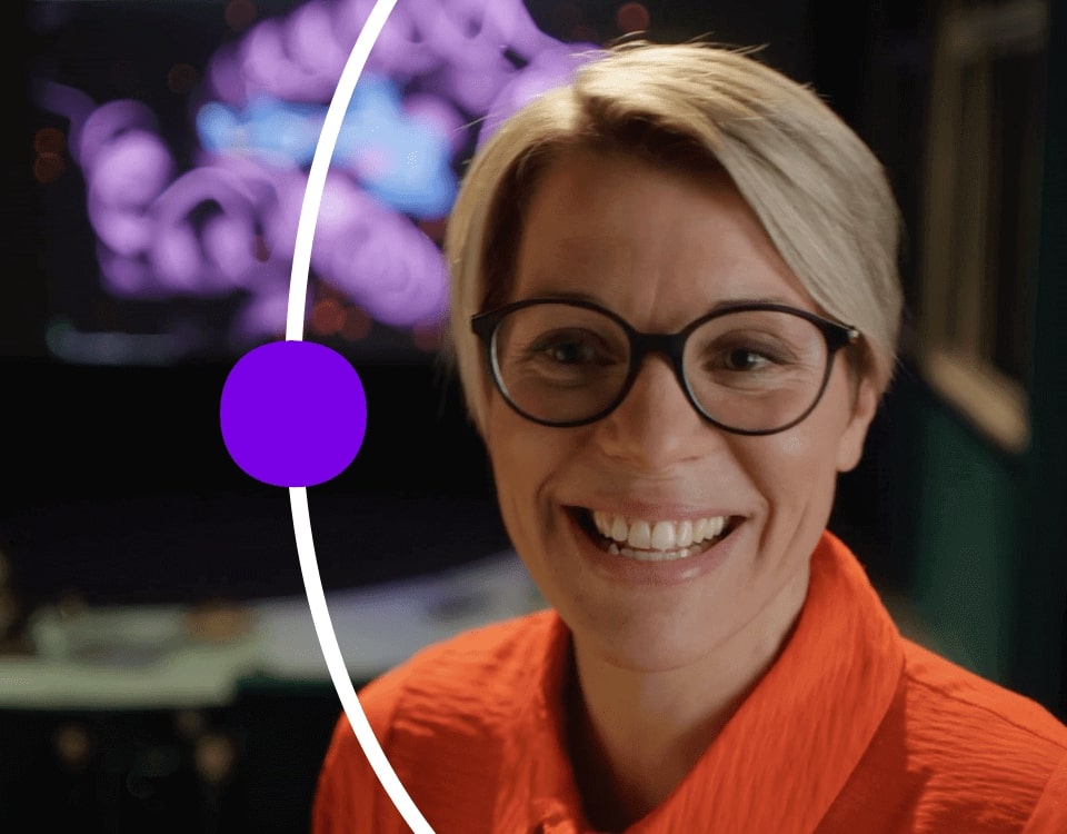 Woman smiling in darkened room with illuminated equipment in the background