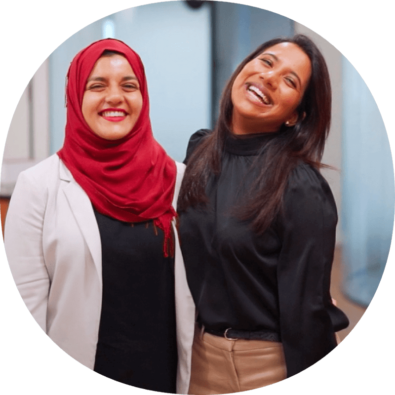 Deux femmes - l'une en hijab, l'autre pas - rient ensemble